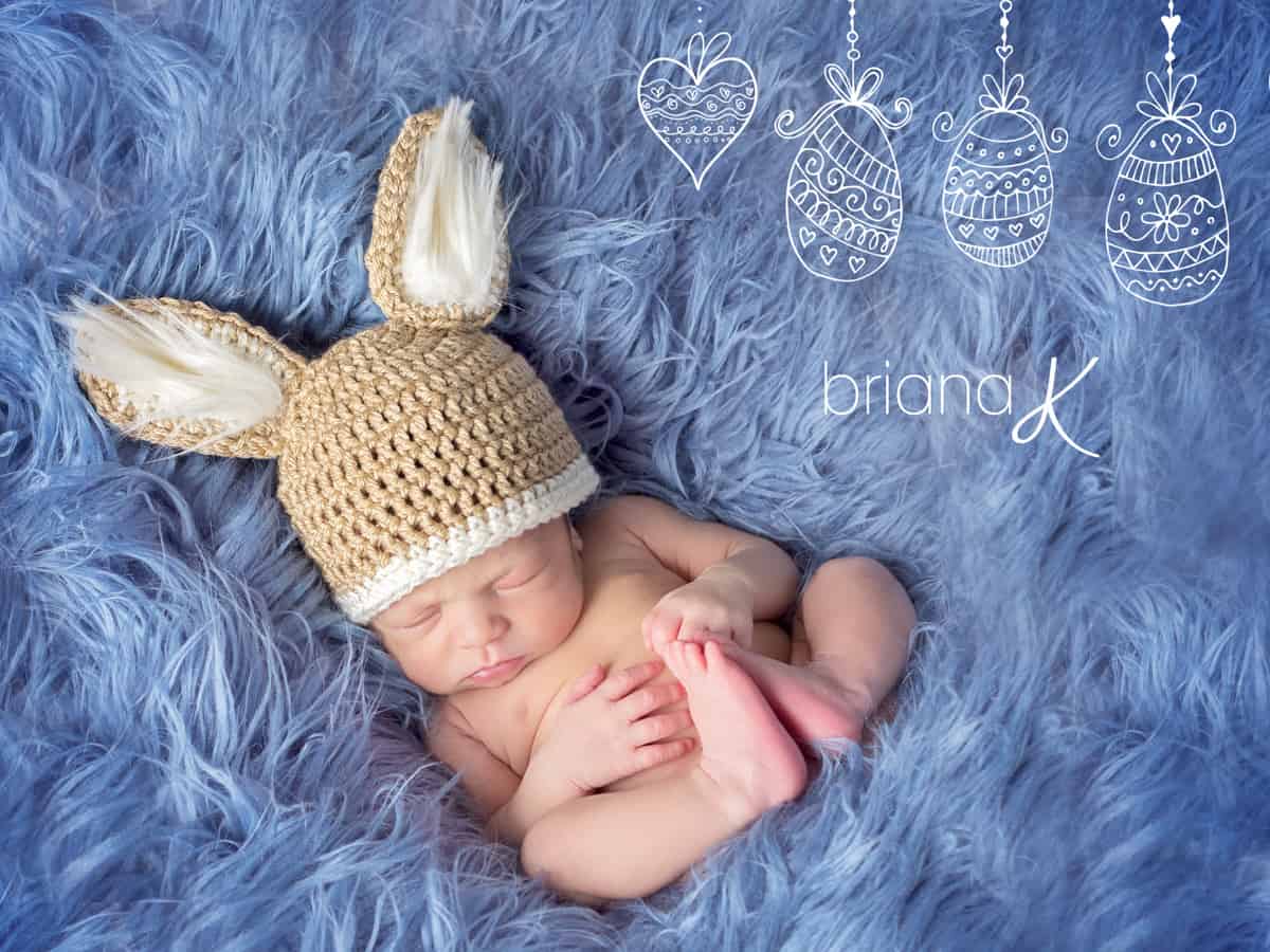 A newborn baby is laying on a blue blanket with a crocheted bunny hat, showcasing the adorable addition of fur.