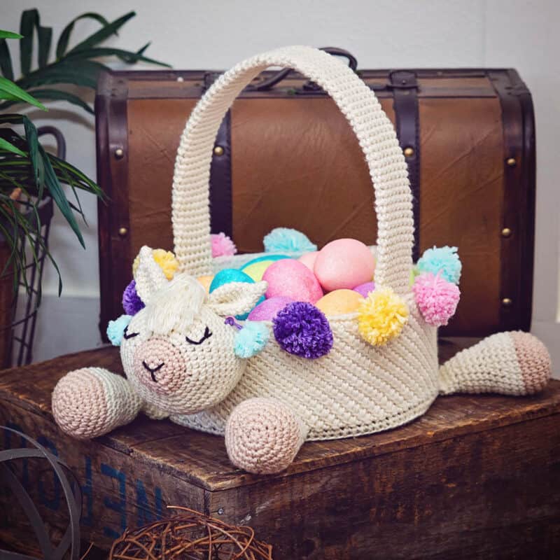 A crocheted Easter basket with a llama design, placed atop a trunk.