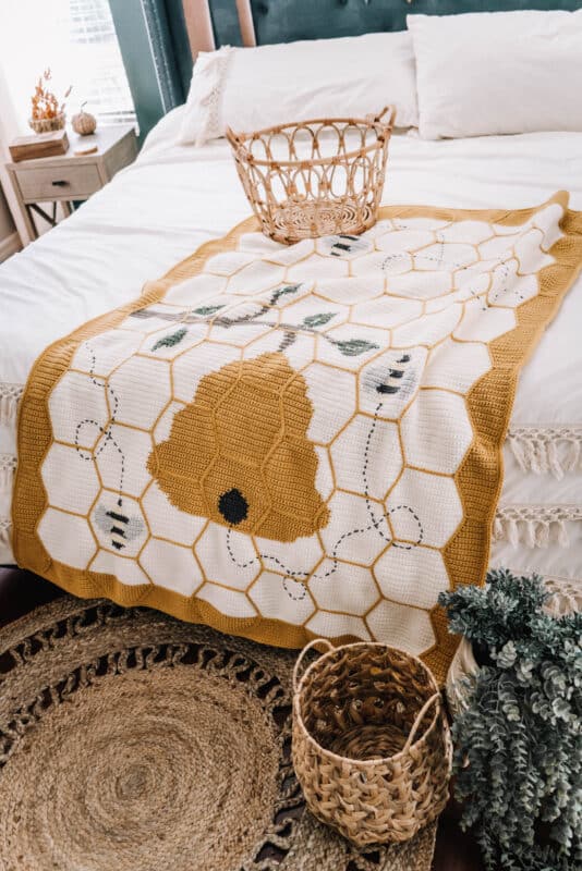 A bed with a beehive blanket on it, featuring the Bee Blanket.