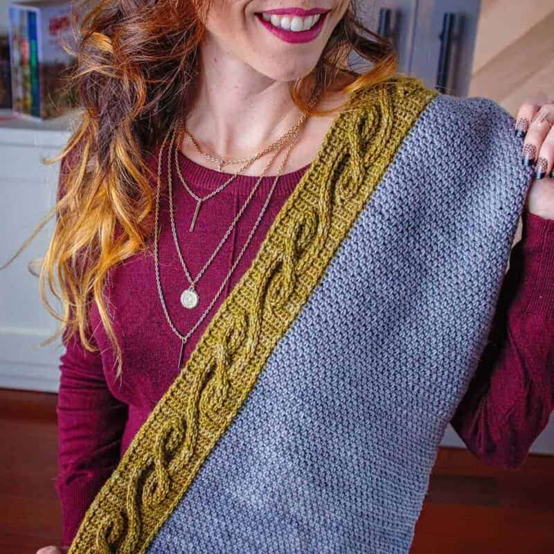 A woman is wearing The Traveling Vine Knit Shawl.