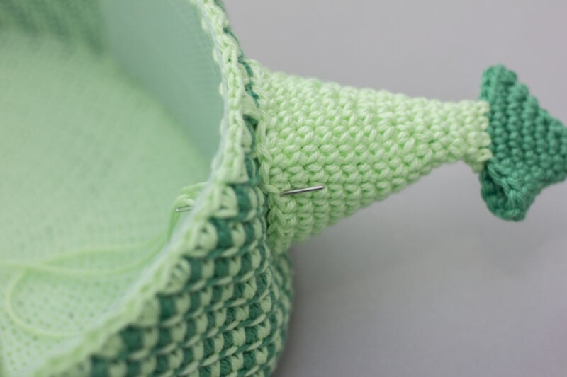 A green crocheted whale basket on a table, perfect as a Dragon Easter Basket.
