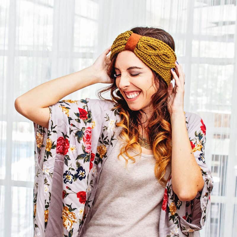 A woman in a floral kimono wearing a knitted headband with a beginner lace knit poncho.