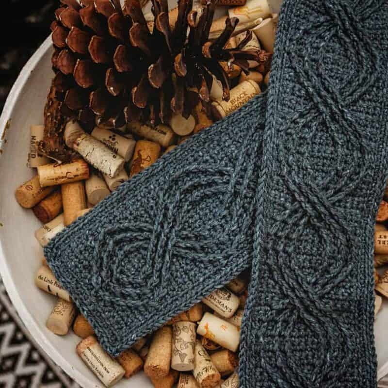 Two knitted scarves in a bowl of wine corks, showcasing beginner lace knitting techniques.