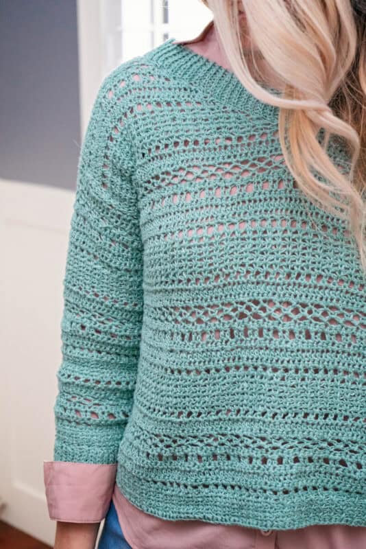 Woman wearing a mint green Sagebrush Lindy Chain Sweater, crocheted with a detailed pattern, partially visible from the back.