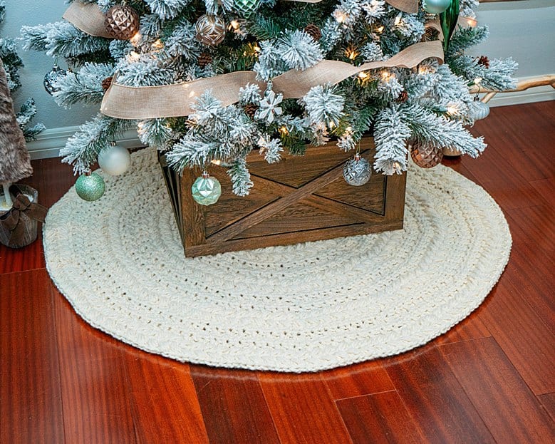 A Christmas tree is standing on a wooden floor.
