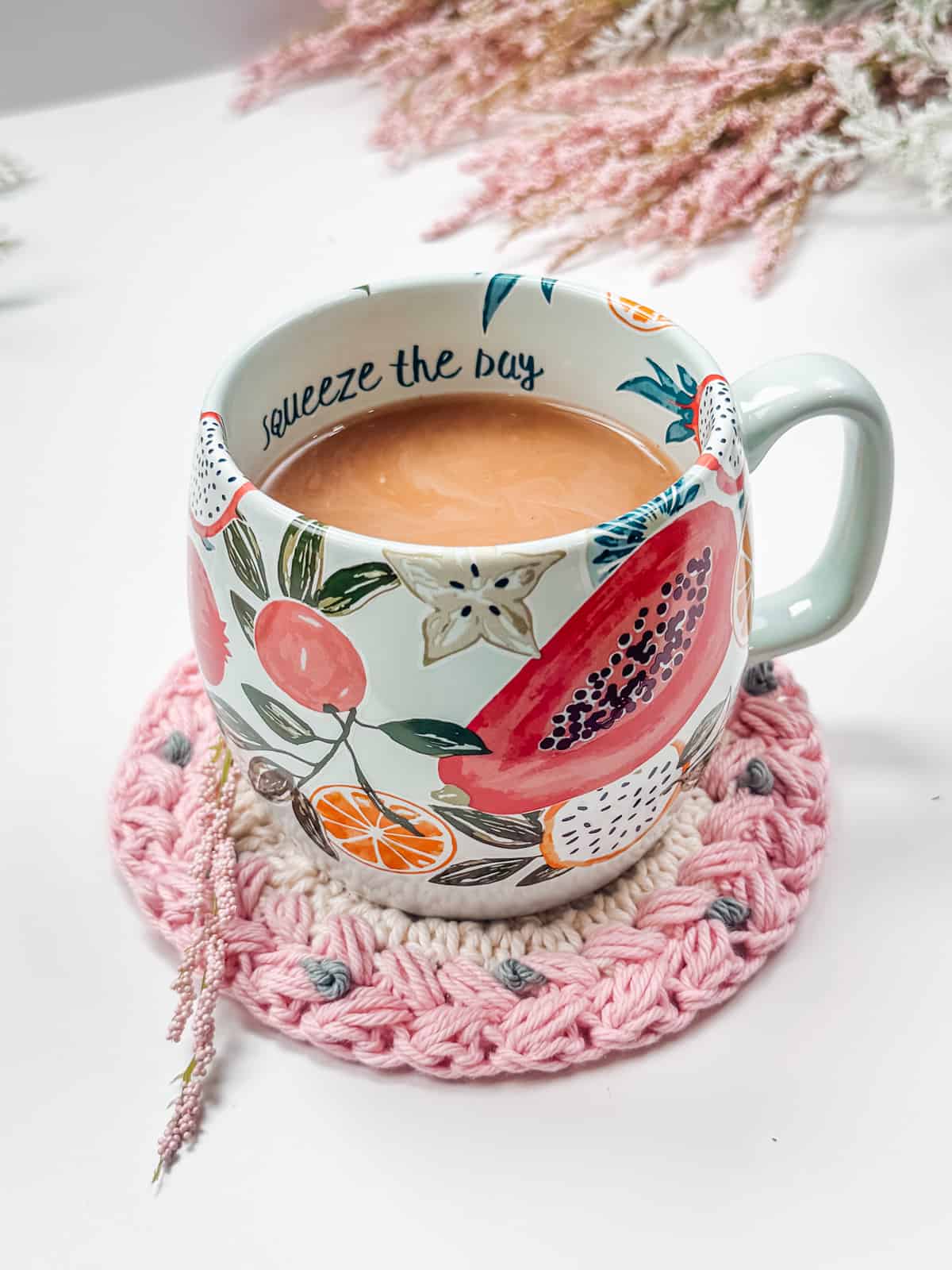 A cup of coffee is sitting on a crocheted coaster.