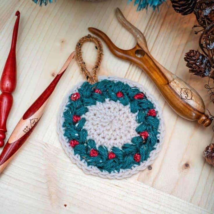 A crochet coaster and two wooden needles for your Crochet Wreath Ornament project.