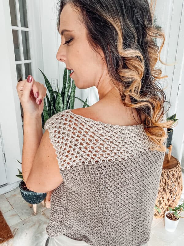 A woman wearing a summer crochet top.