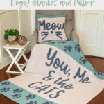 Armchair with a cozy crochet blanket that reads "You, Me & the Cats," and a matching pillow with "Meow," both in teal and cream and adorned with playful paw prints—perfect for any cat or dog lover.
