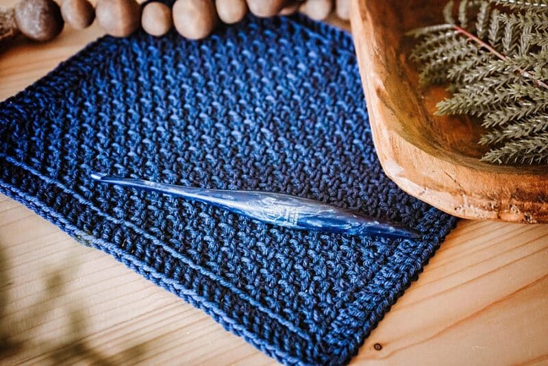 a textured blue crochet fabric and crochet hook