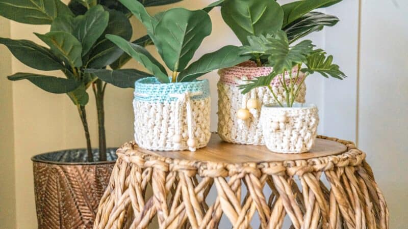 Three Teton crochet pots on a wicker stool.