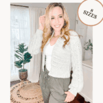 Woman wearing a light crochet cardigan and green pants stands in a bright room. Text overlays promote the free Get Comfy Crochet Cardigan Pattern and video tutorial, available in 8 sizes.