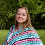A woman wearing a colorful crocheted poncho.