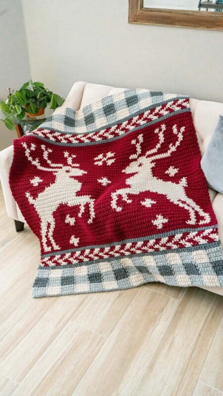 A prancing reindeer blanket on a couch.