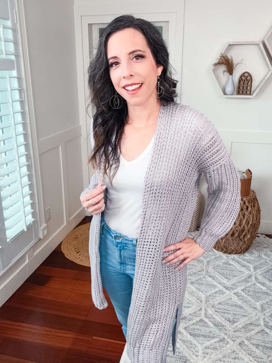 Woman in a cozy Campside Cardi and jeans smiling indoors.