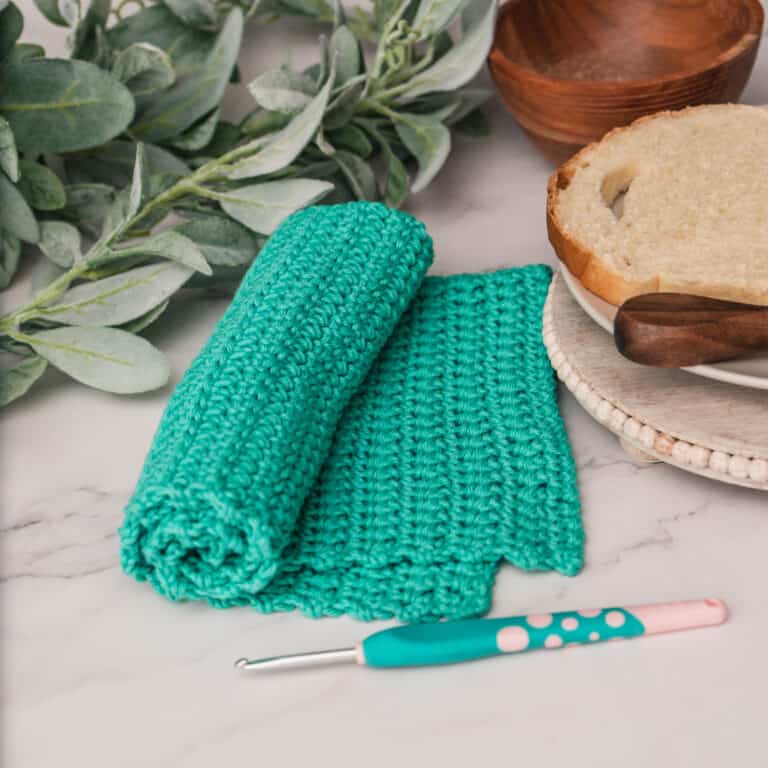 A toothbrush is next to a green crocheted dishcloth with extended single crochet.