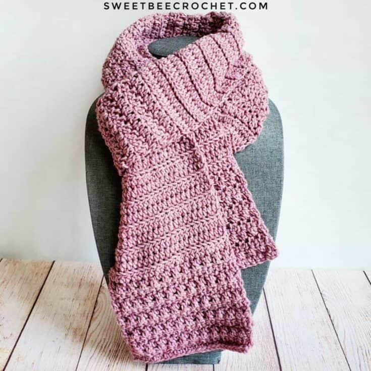 A pink crochet scarf on a mannequin.