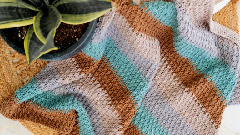 A crocheted tote bag featuring an Alpine Stitch plant motif.