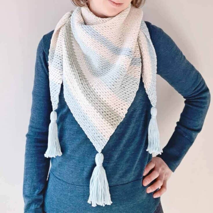 A woman wearing a crochet scarf with tassels.