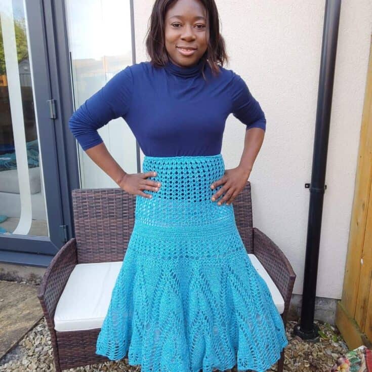 A woman is posing for a picture in a blue crocheted skirt.