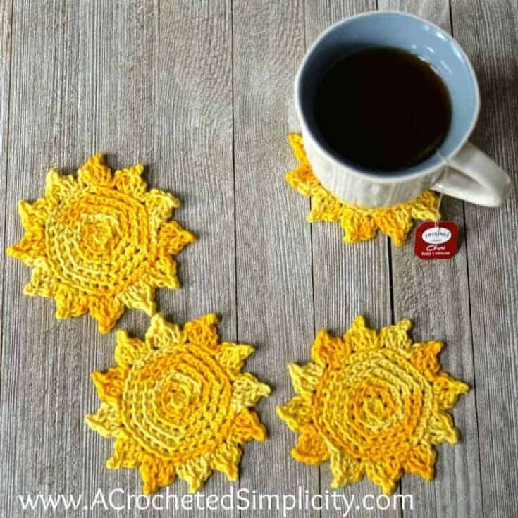 Three crocheted sun coasters next to a cup of coffee.