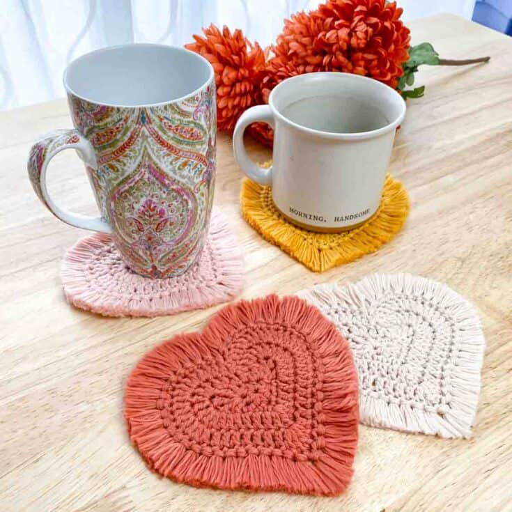 Three crocheted heart shaped coasters on a wooden table.