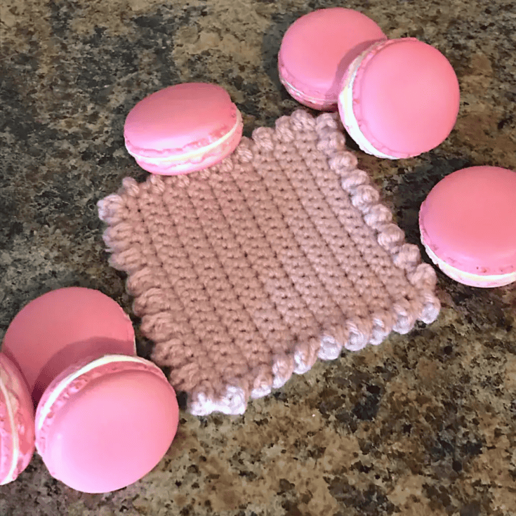 Crocheted pink macarons on a countertop.