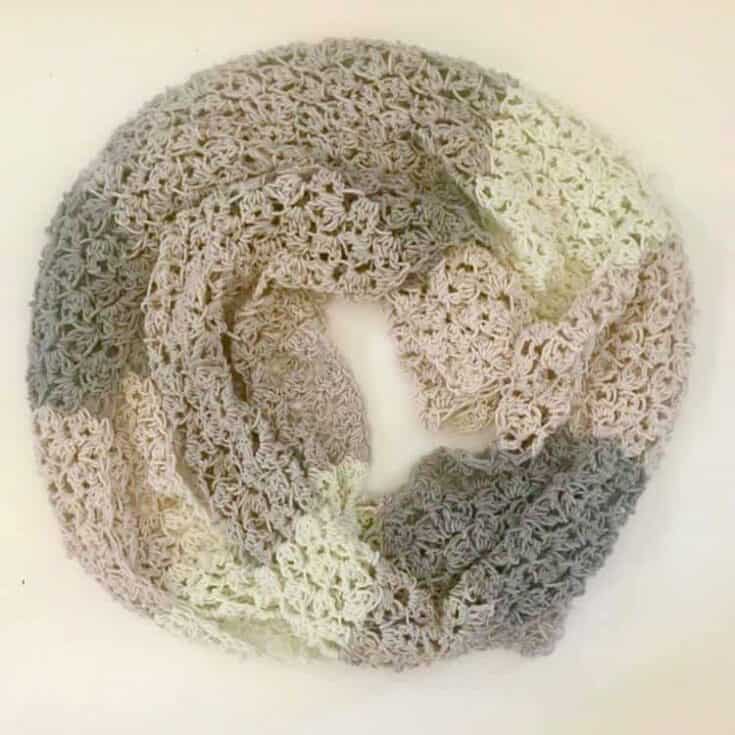 A crocheted infinity scarf on a white surface.