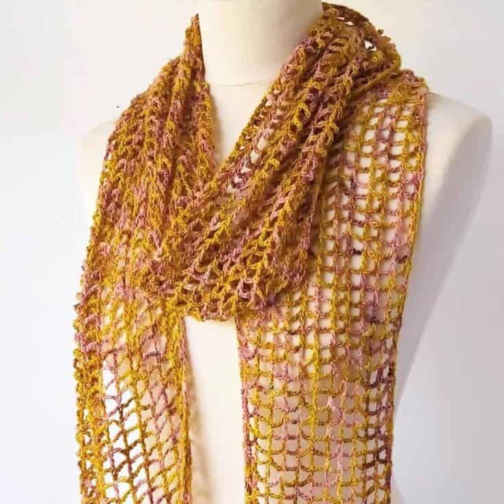 A yellow and pink crocheted scarf on a mannequin mannequin.