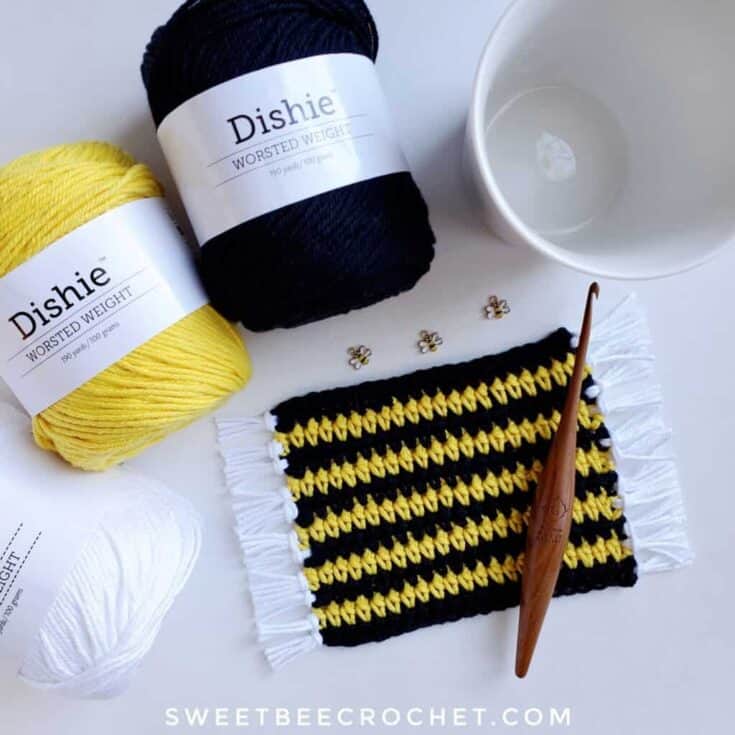 A yellow and black crochet bee pattern with a cup of coffee next to it.