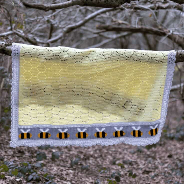 A bee blanket hanging from a tree in the woods.