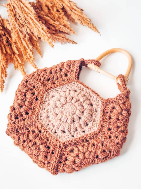 A crocheted bag with a wooden handle.