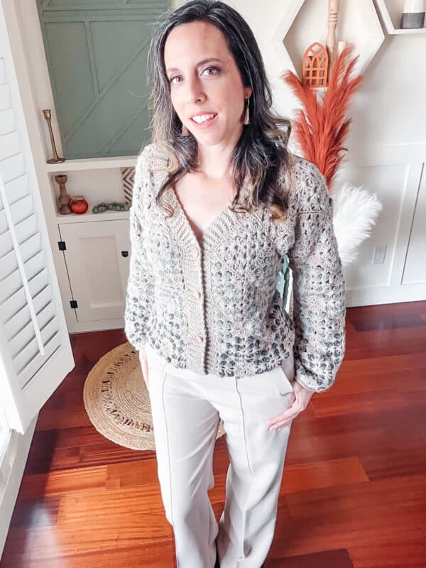 A woman in a beige crochet Granny Square Cardigan standing in a room.