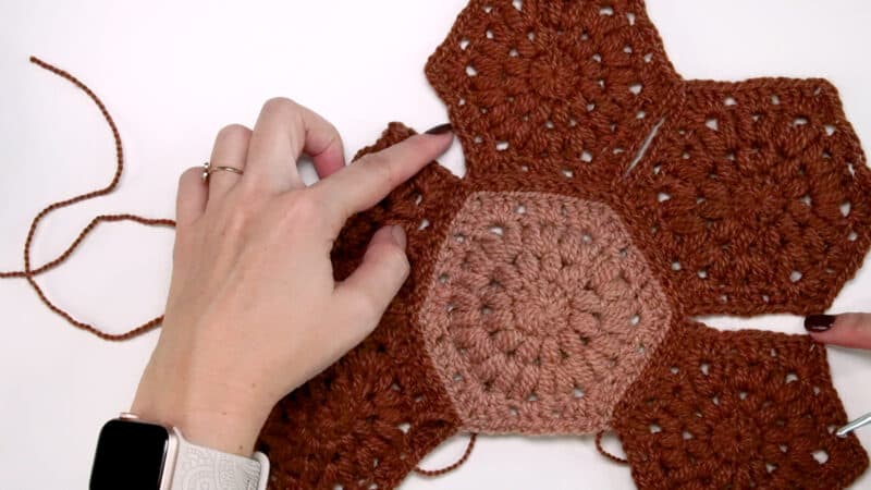 A person is making a crocheted hexagon.