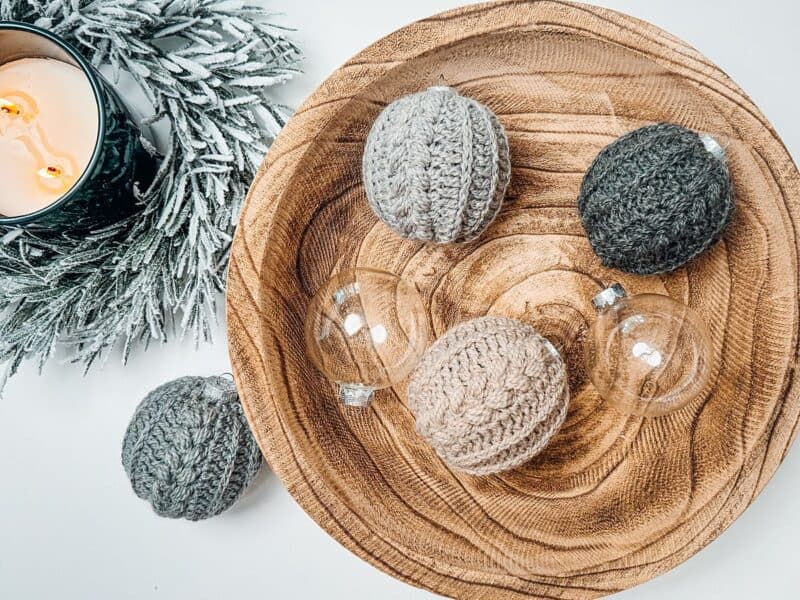 Crocheted Christmas balls on a wooden plate with a crochet pattern.