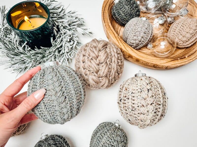 Crochet Christmas ornaments on a table next to a candle, showcasing intricate crochet patterns.