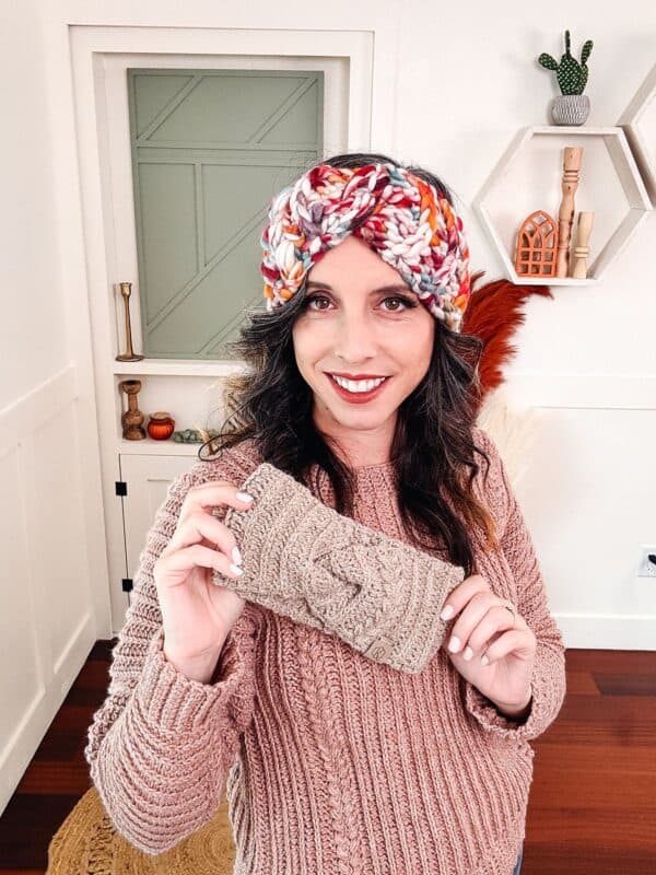 A woman in a crochet sweater holding a turban.
