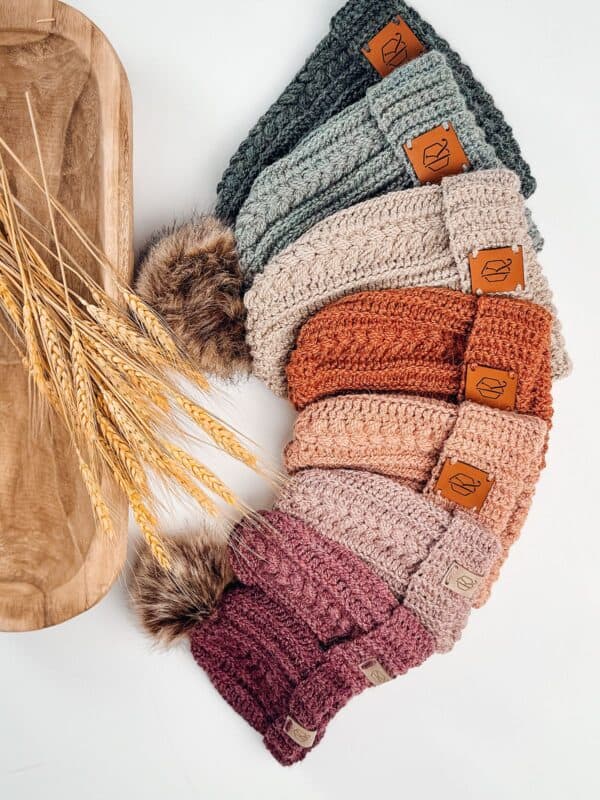 Four different colored crochet beanie hats with pom poms that match beautifully.
