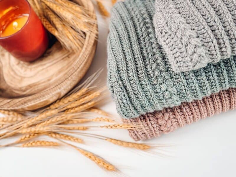 Two knitted hats and a candle on a white background.