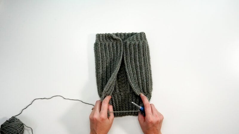 A person is knitting a bag with a needle and crochet.