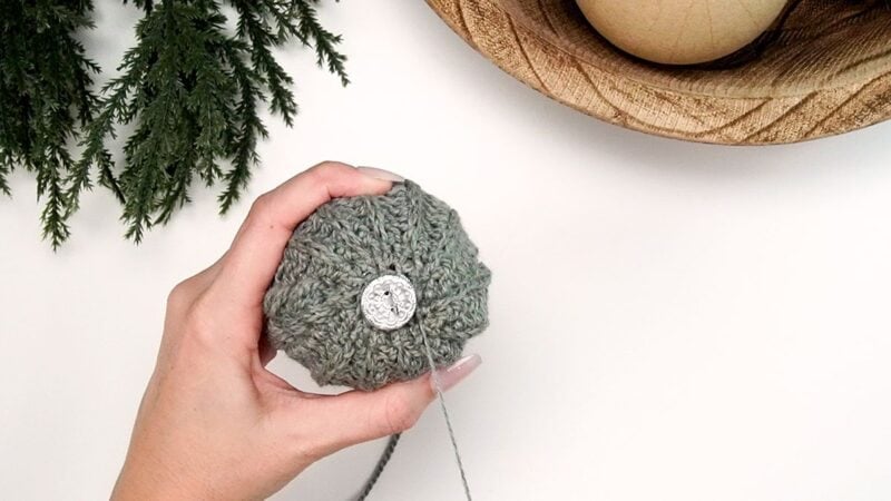 A person holding a yarn ball in front of a crochet tree.