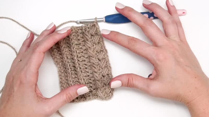 A pair of hands holding a knitting needle.
