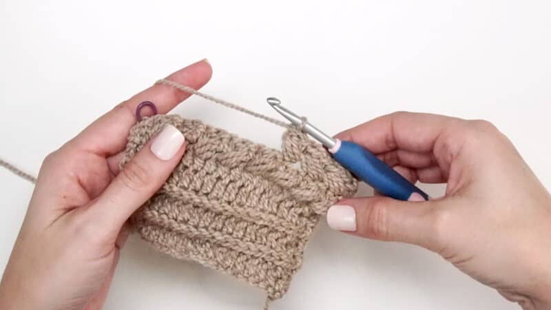 A person is using a crochet hook to make a stitch.