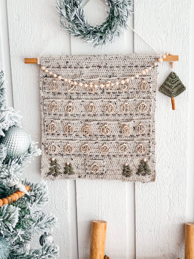 A crochet Christmas advent calendar with a granny crochet stocking hanging on a wall.