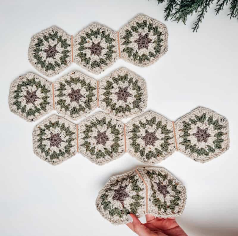 A person is holding a set of crocheted hexagon coasters.