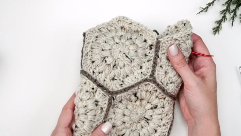 A person is holding a crocheted child sweater.