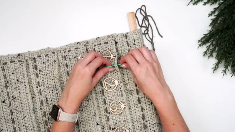 A woman is knitting a blanket with a crochet hook in the style of granny crochet.