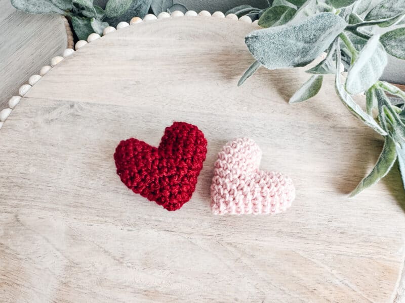 A charming wooden table adorned with two crocheted hearts.