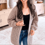 A woman in a beige Hummingbird Crochet Cardigan stands indoors, smiling, with shelves of yarn in the background. Text reads “Hummingbird Crochet Cardigan” and website “www.brianakdesigns.com”.