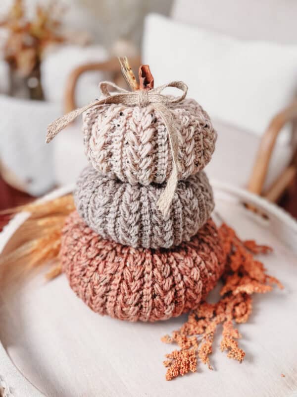 A stack of knitted pumpkins on a white tray.